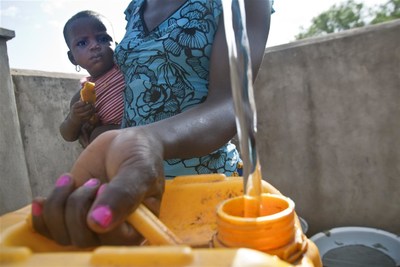 A woman with a girl toddler fills a jerrycan at a community water point in Ouéréguékaha Village in Côte d'Ivoire. After four years, households again have access to safe, piped water, thanks to a UNICEF programme. (c)UNICEF/UNI94496/Guoegnon (CNW Group/UNICEF Canada)