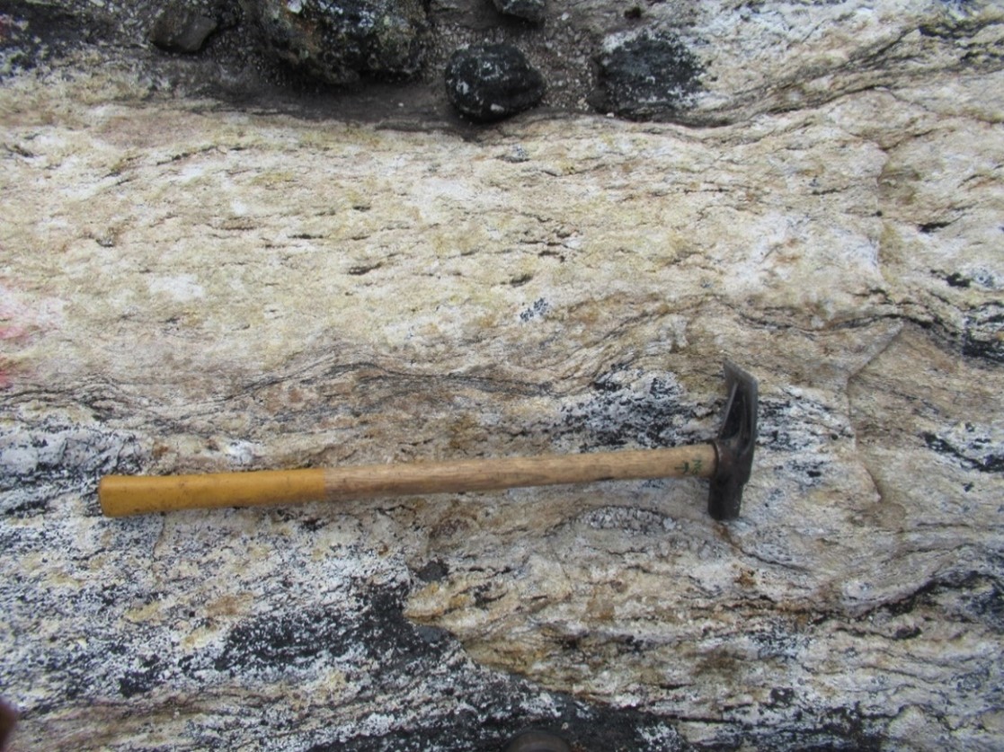 Highly strained granitic pegmatite showing an East-West foliation and significant uranophane mineralization located in the Katjuk (Arrow) Zone. Photo